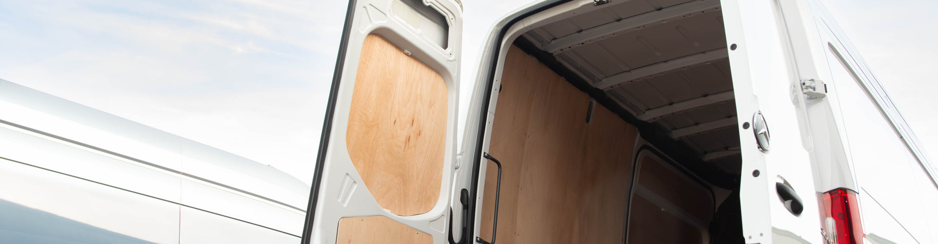 Van with open cargo door on a road with a clear sky.